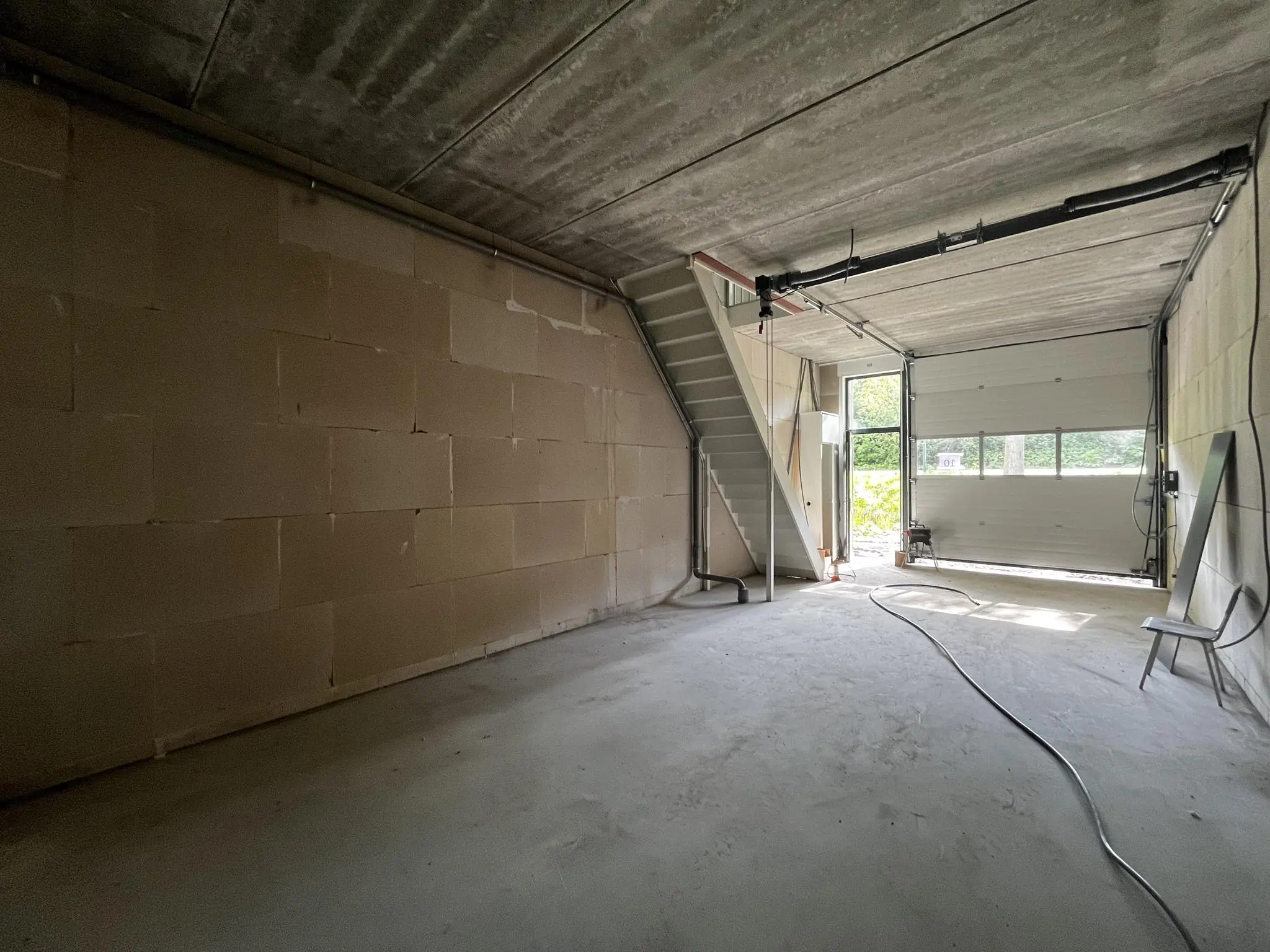 Lege garage of opslagruimte aan de Broekdijk West met trap naar boven en openstaande roldeur.